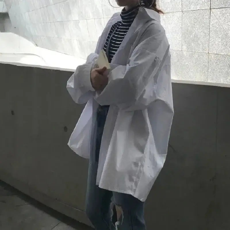 Zadily minimalist oversize white shirt on a woman, styled with casual jeans and a striped top, perfect for spring.