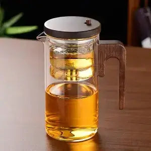 Heat-resistant glass teapot with stainless steel infuser and wooden handle, showcasing brewed tea.