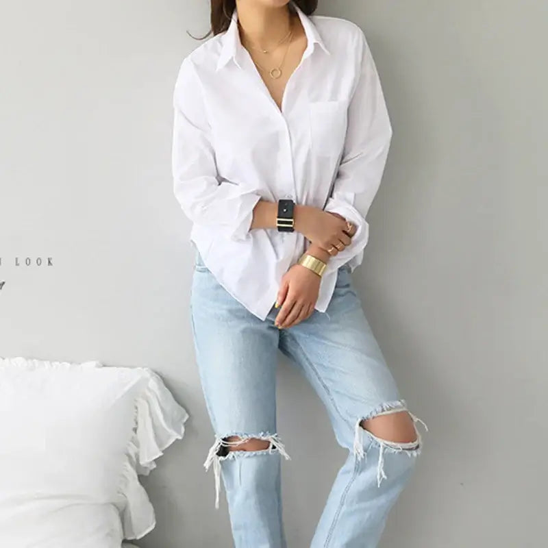 Elegant white blouse with turn-down collar, paired with distressed jeans, suitable for casual or office wear.