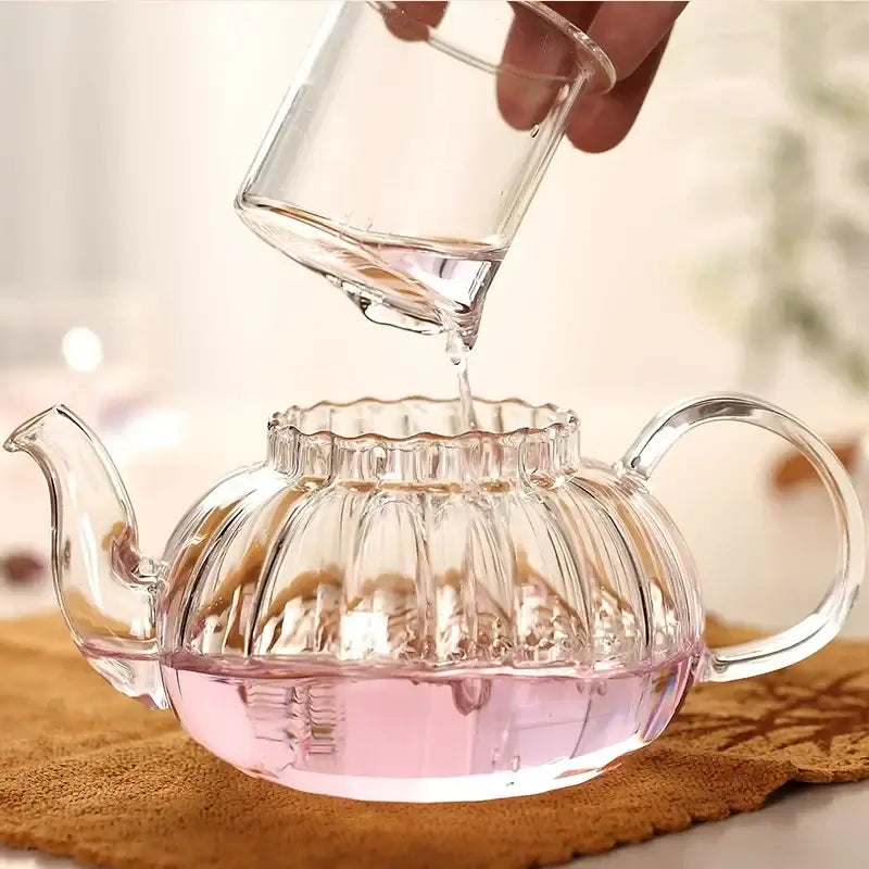 600ml striped pumpkin-shaped glass teapot with infuser, pouring hot water into it, showcasing heat-resistant design.