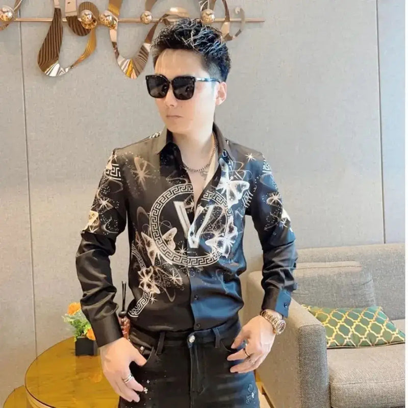 Men's stylish black printed shirt with flair sleeves, worn with sunglasses in an elegant setting.