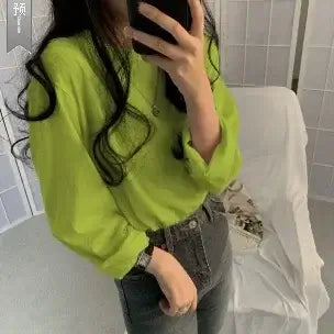 Stylish woman wearing a loose-fit lime green long sleeve shirt paired with high-waisted jeans.