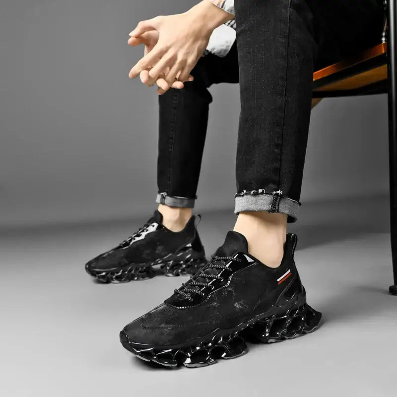 Black breathable male sneakers with unique sole design, perfect for casual and athletic wear, shown on a seated model.