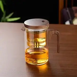 Heat-resistant glass teapot with stainless steel infuser, ideal for tea lovers, showcasing tea brewing.