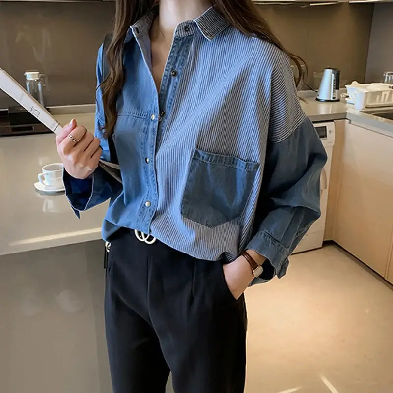 Spring women's loose fit denim shirt with long sleeves and patchwork design, styled casually in a modern kitchen.