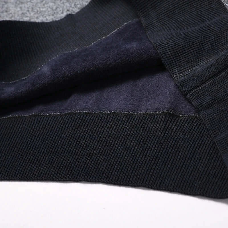 Close-up of the fabric texture and ribbed hem of a men's long sleeve sweater, showcasing high-quality knitting.