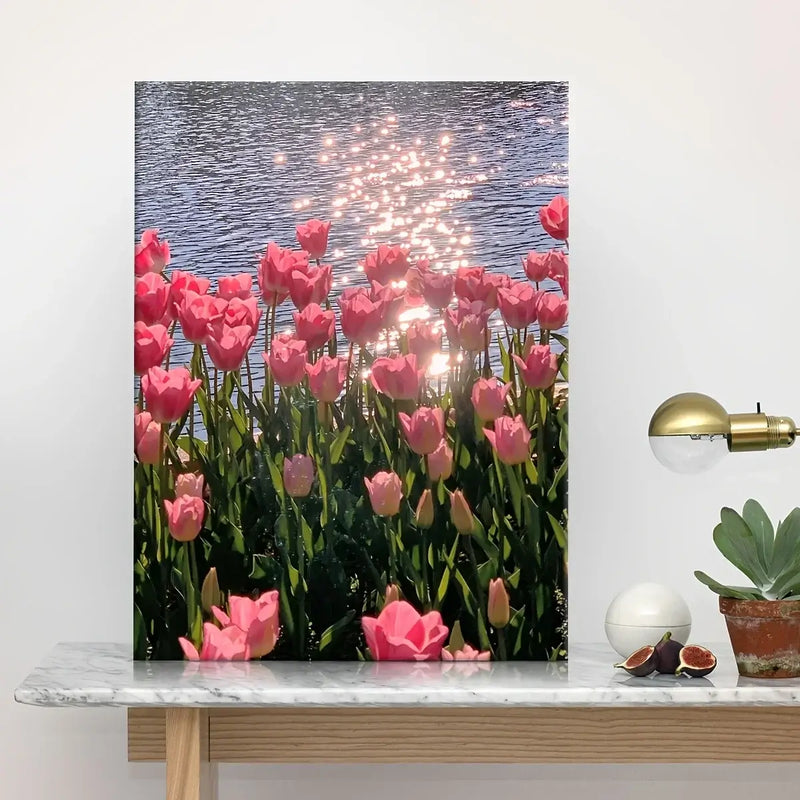 Framed canvas poster featuring pink tulips by a sparkling water surface, ideal for home decor in living room or office.