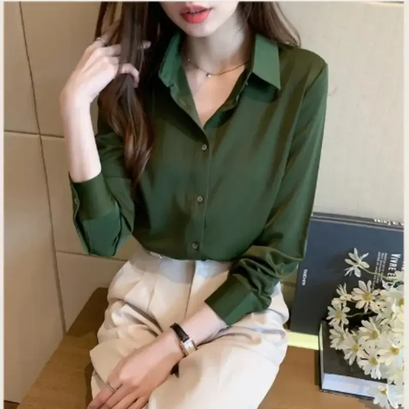 Slim-fit green satin blouse on a woman, styled with cream trousers, perfect for casual or office wear.