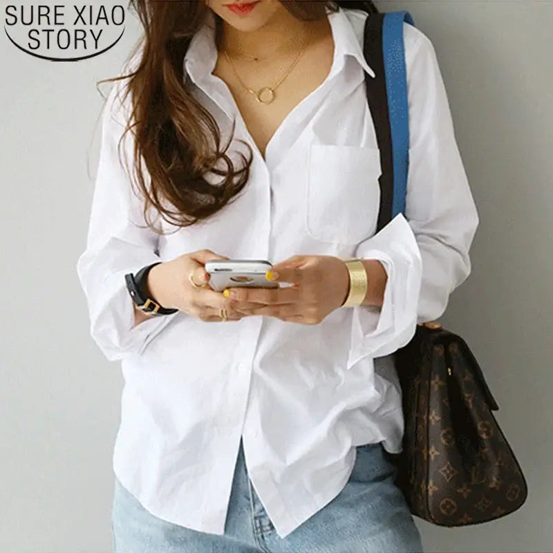 Elegant white blouse with turn-down collar, perfect for casual office wear, paired with stylish accessories.