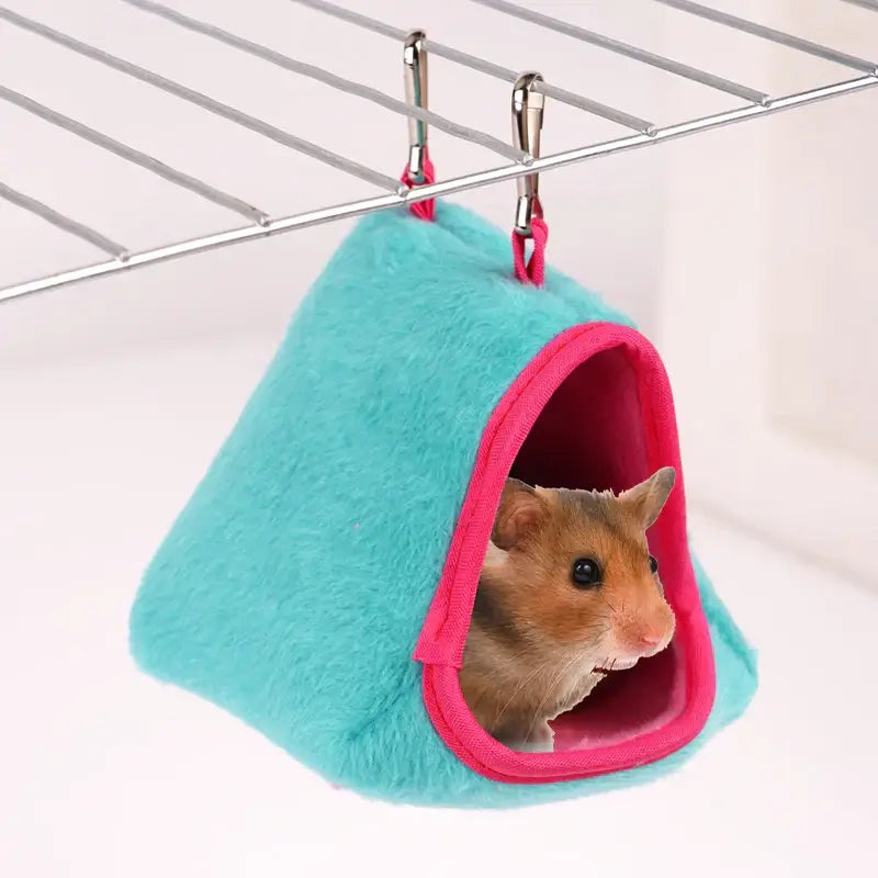 Cozy turquoise and pink hamster hammock suspended in cage, featuring a content hamster inside.