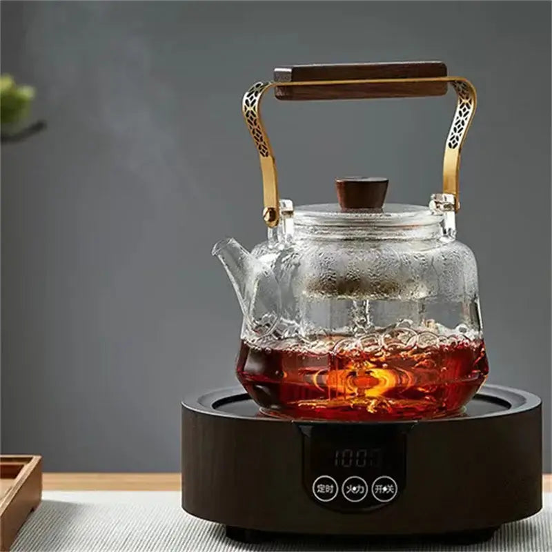 Japanese heat resistant glass teapot with copper wood handle brewing tea on an electric kettle.